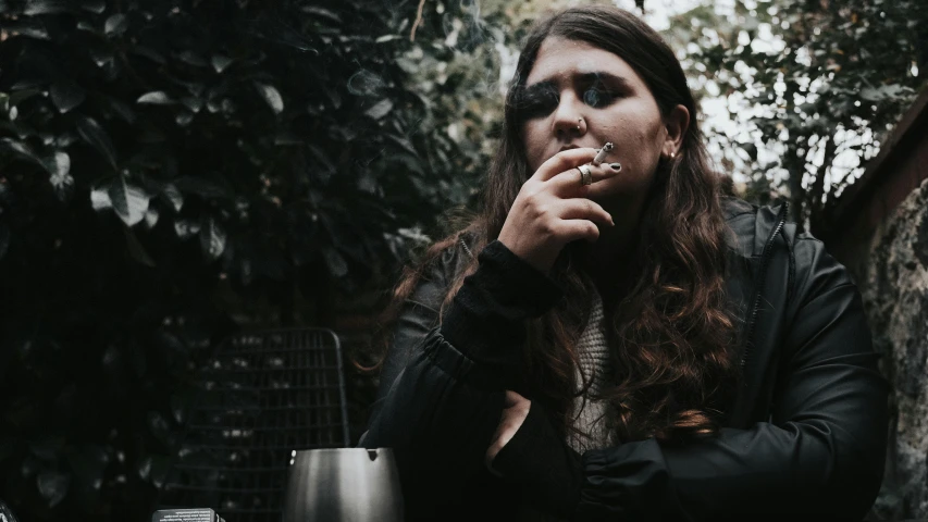 a young man is smoking while standing outside in the rain