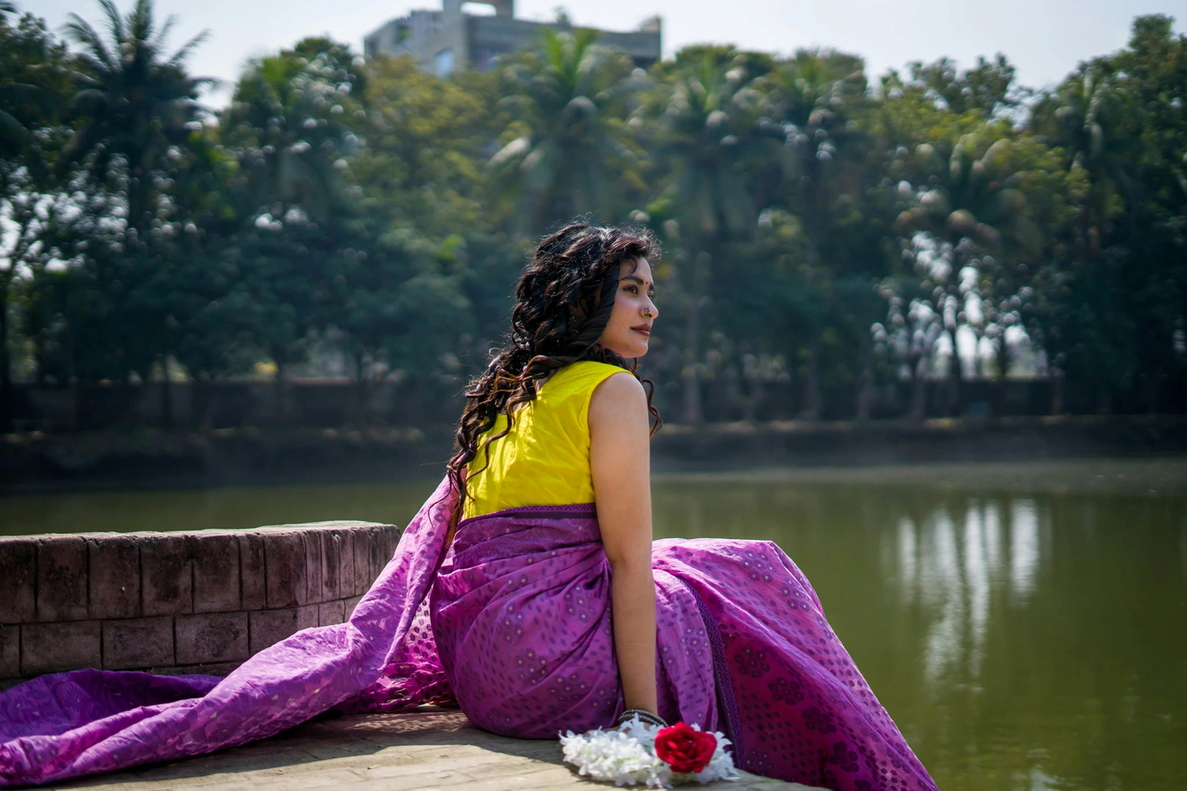 a woman with a flower is sitting on a dock