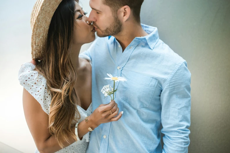 young couple kissing, holding daisy, with white background