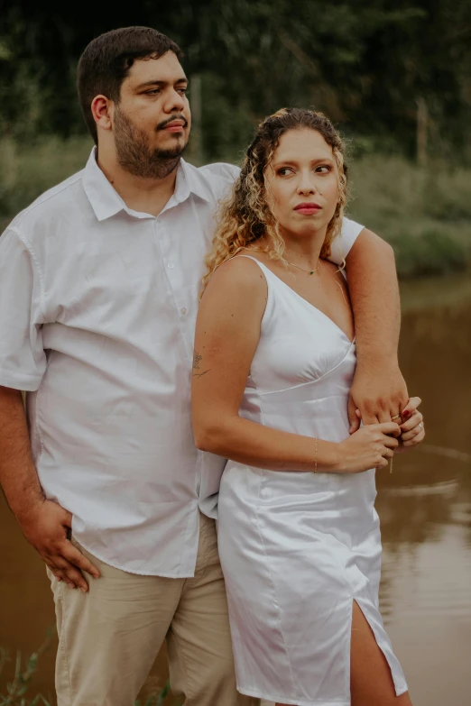 a man and woman standing beside a body of water