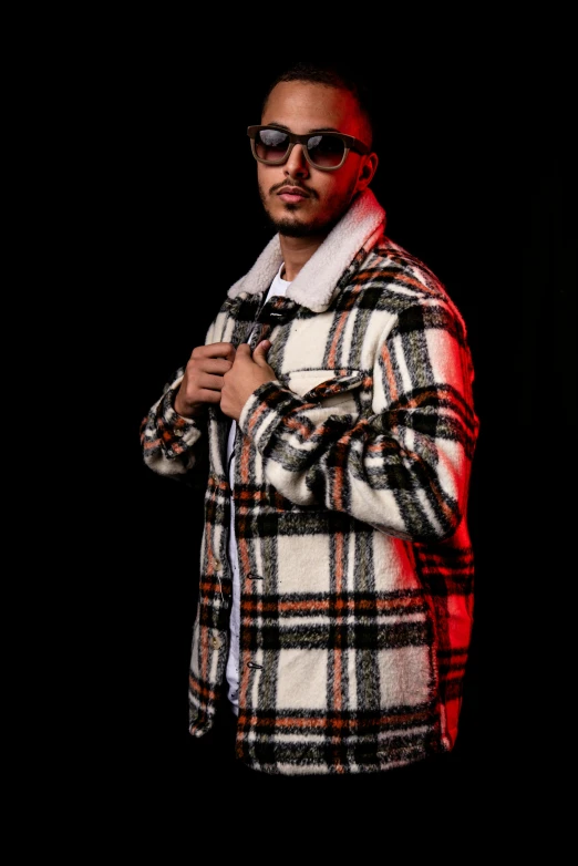 a man wearing sunglasses and jacket with dark background