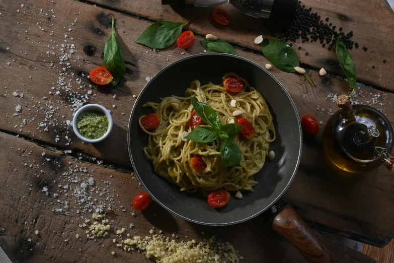 a plate full of pasta next to a bowl with basil on it