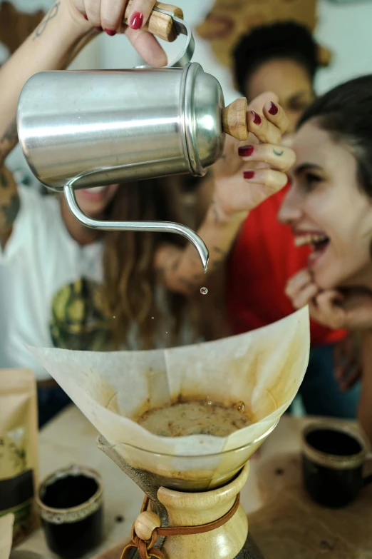 two women sitting down and a woman is pouring coffee