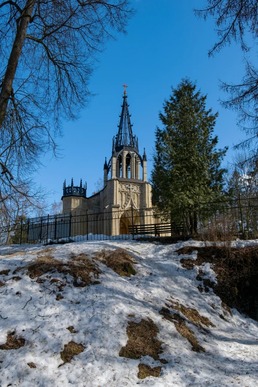 a church on top of a snowy hill with a tree in the foreground