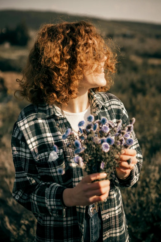 a young woman is standing in a field holding flowers