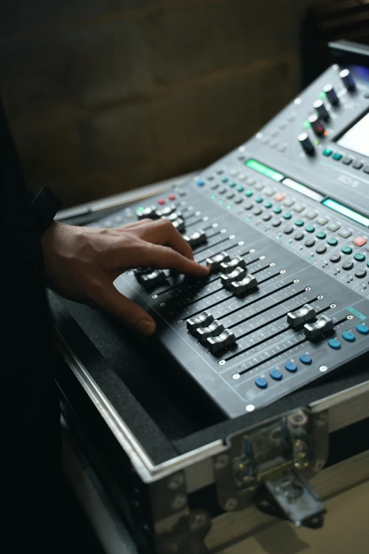 a mixing board with multiple ons and a person's hand touching it