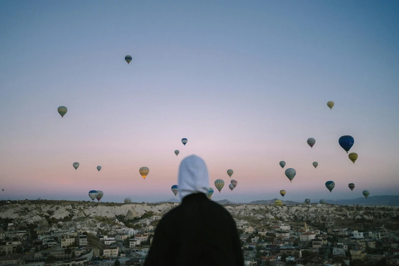 a person standing in front of a large number of  air balloons