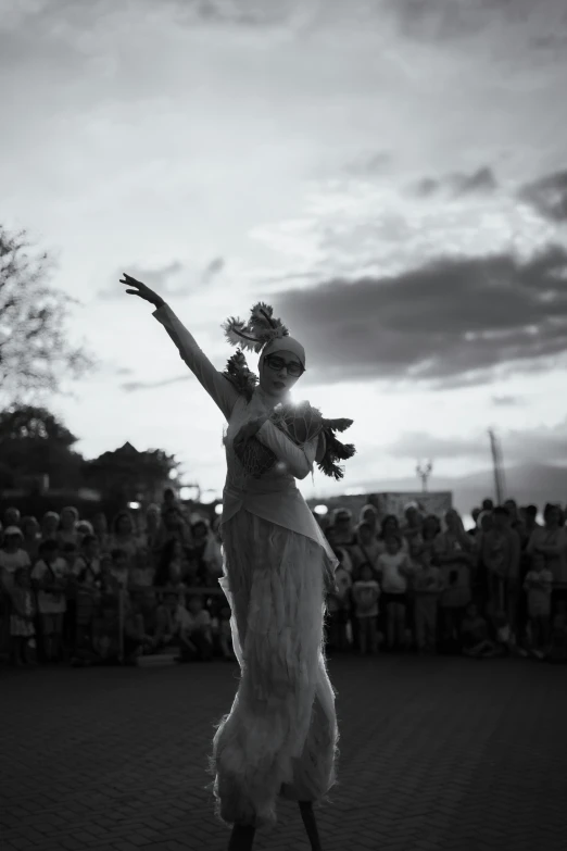 a woman wearing white is dancing in front of people