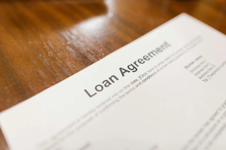 the loan agreement is sitting on top of a wooden table