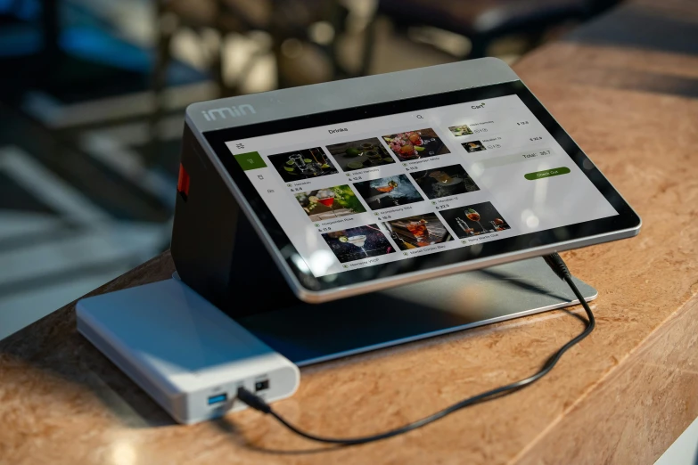 a small tablet on a wooden table with a charger