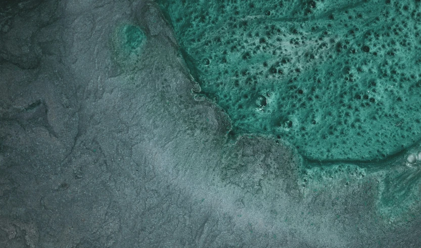 an overhead view of water surrounded by sand