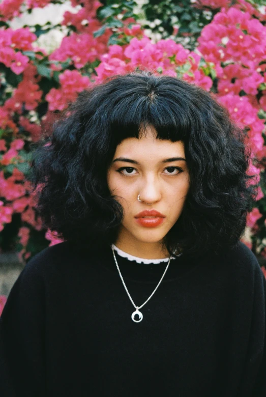 a young woman with an afro standing next to flowers