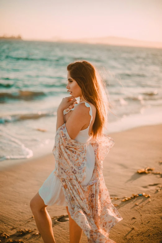 a woman walks along the beach, at sunset