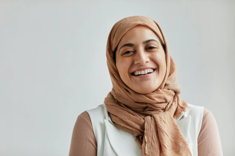 an oriental woman smiling, wearing a beige shawl