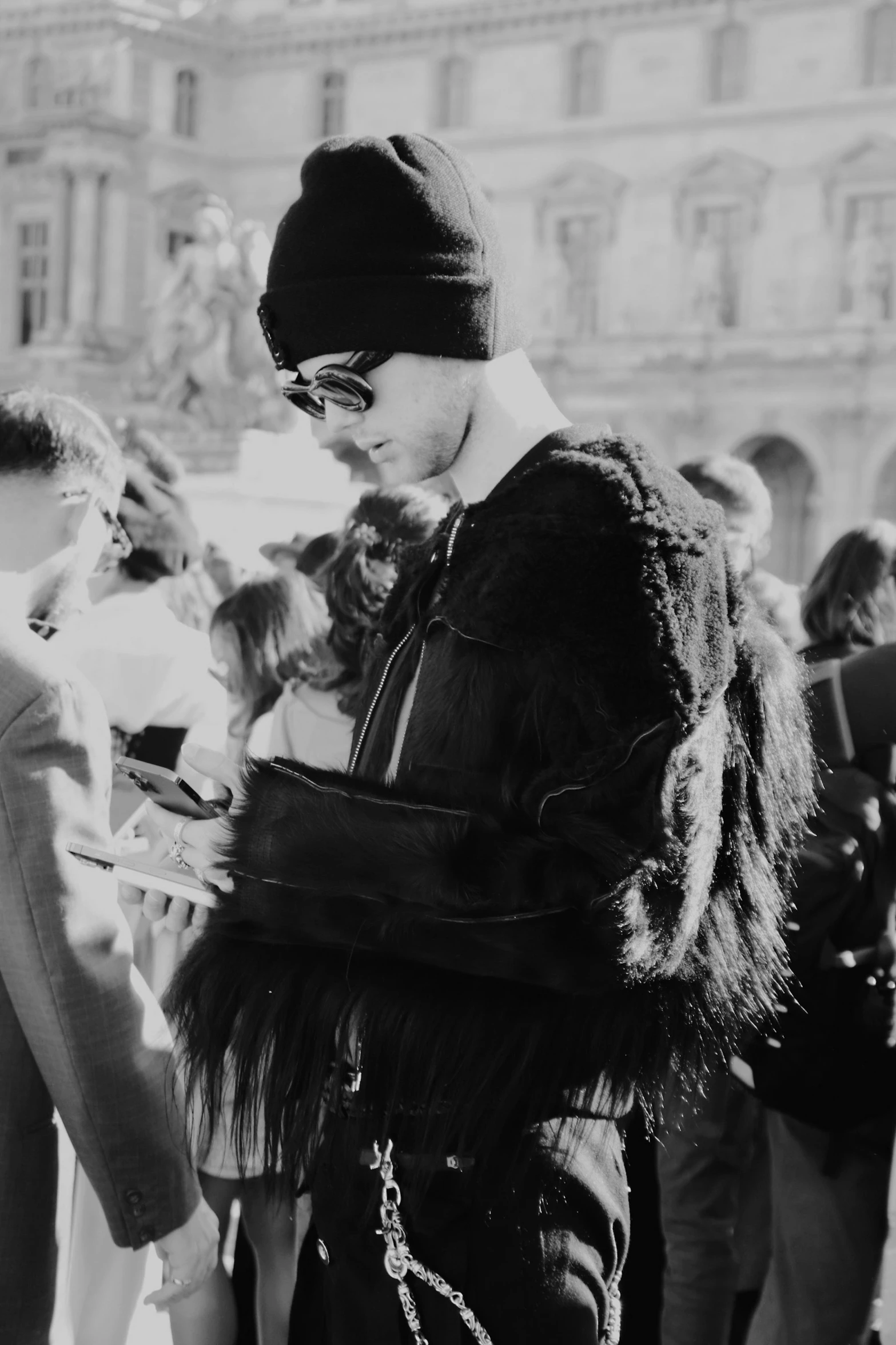 a woman in a fur coat and hat standing next to a crowd