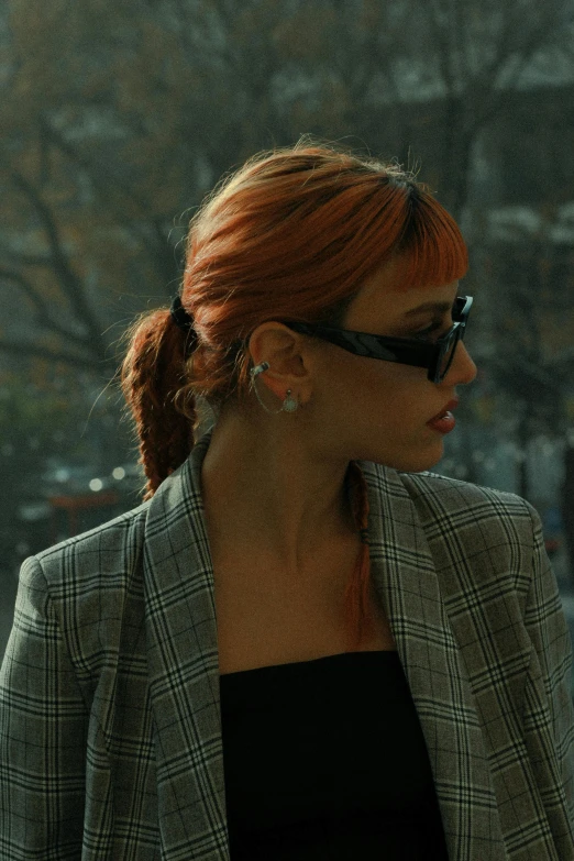 a woman in sunglasses and jacket walking down a street