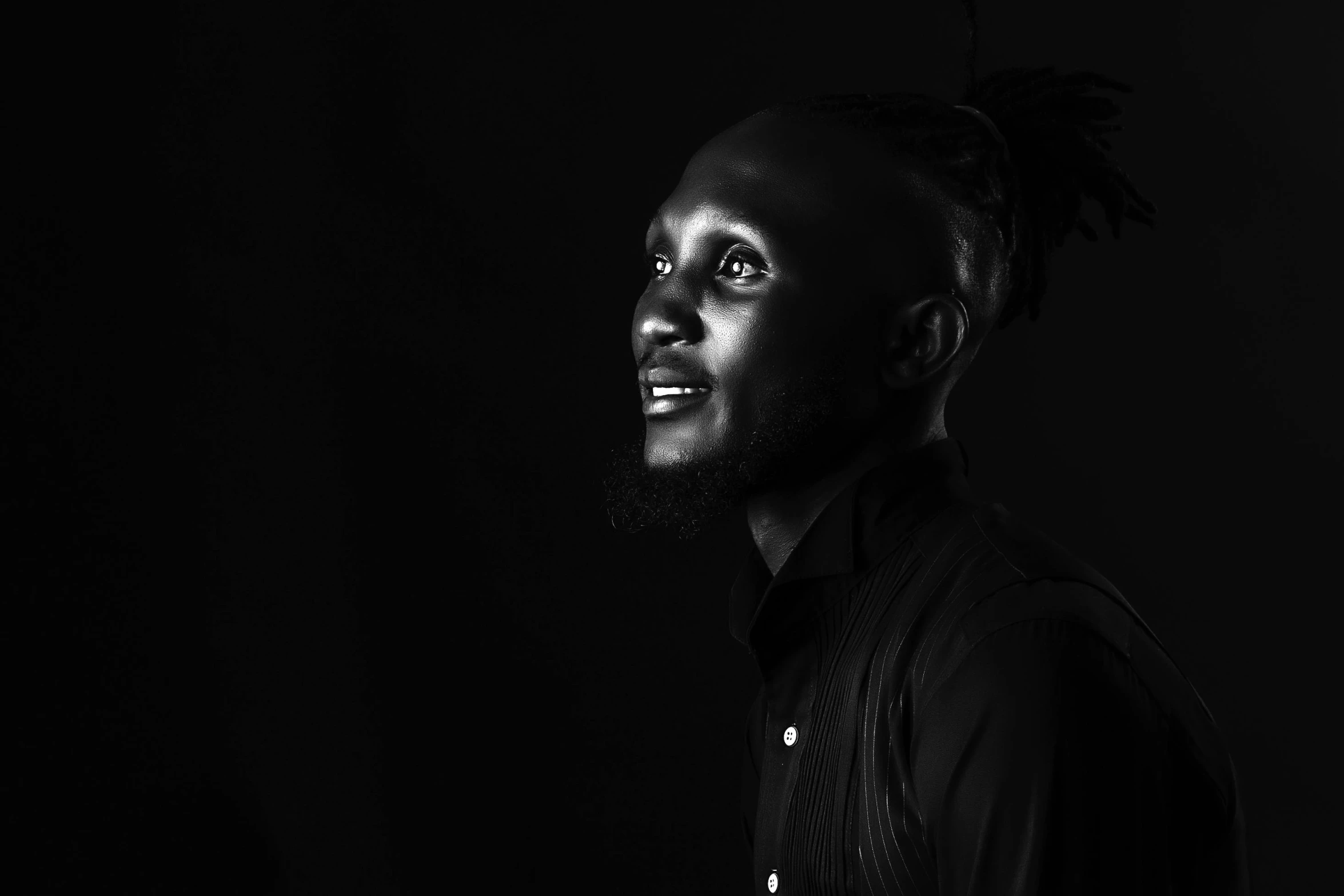 man with dreadlocks standing in front of dark background