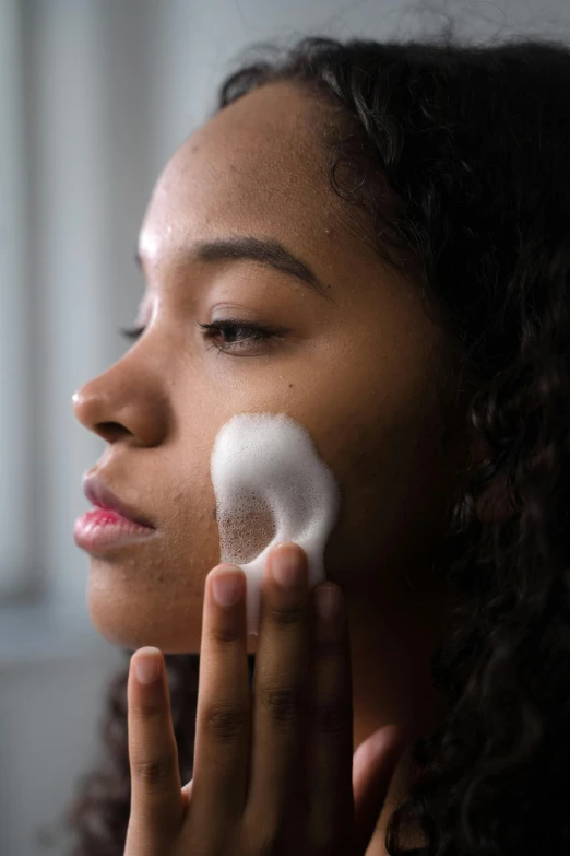 a woman brushes her face with a foam