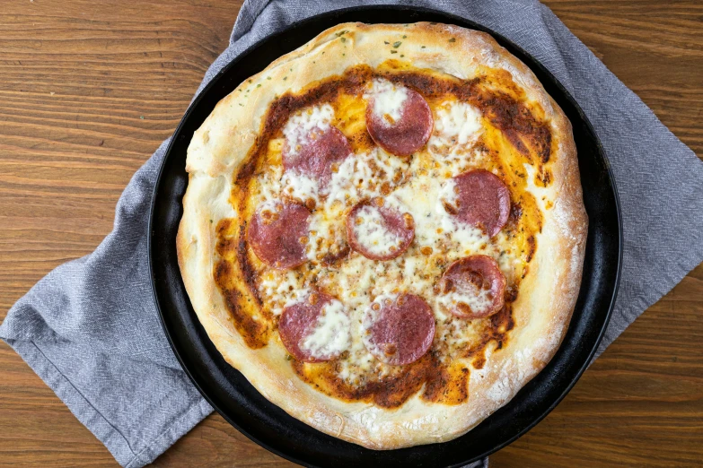 a pepperoni pizza sitting on top of a pan on a table