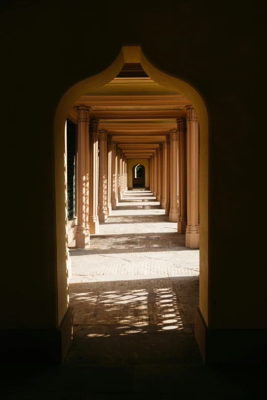 a walkway with rows of archways and stone floor