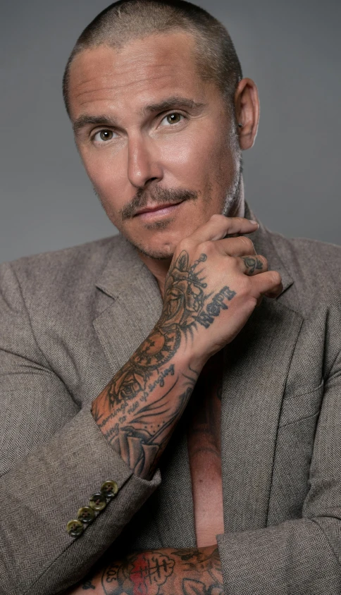 a man in a suit with a tattoo on his arm