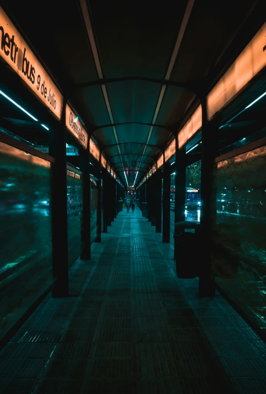 the walkway of a metro station is empty at night