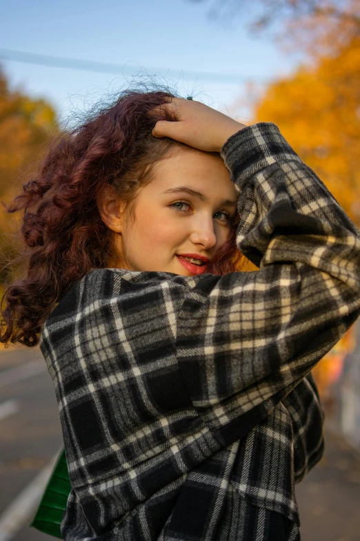 a young woman is posing on the side walk