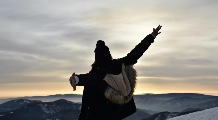 a person wearing a hat on top of a snow covered mountain