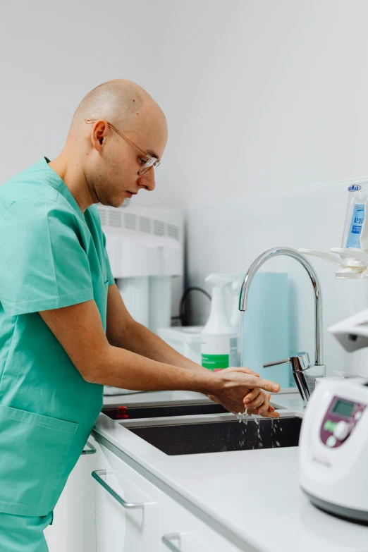 a man with bald head washing dishes in the kitchen