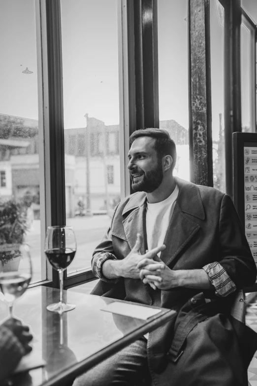 man with his hand on his lap and looking out a window