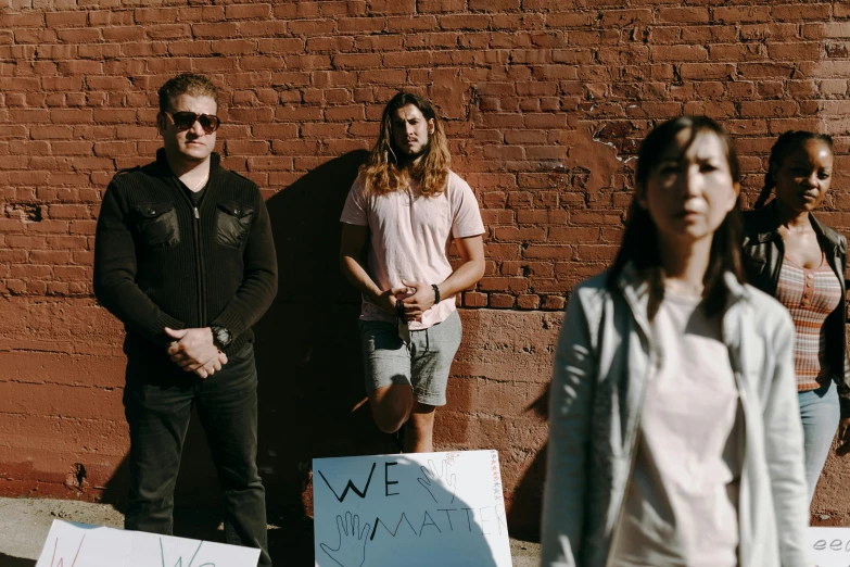 several people standing together in front of a brick wall