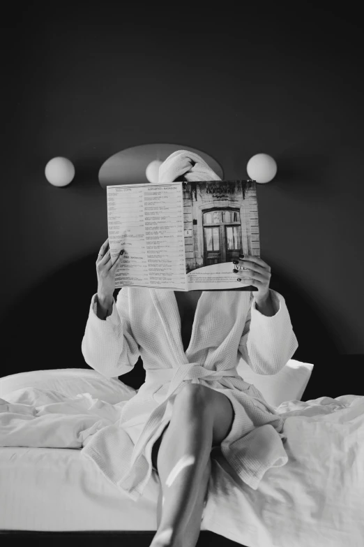 a woman sitting in bed with an open newspaper