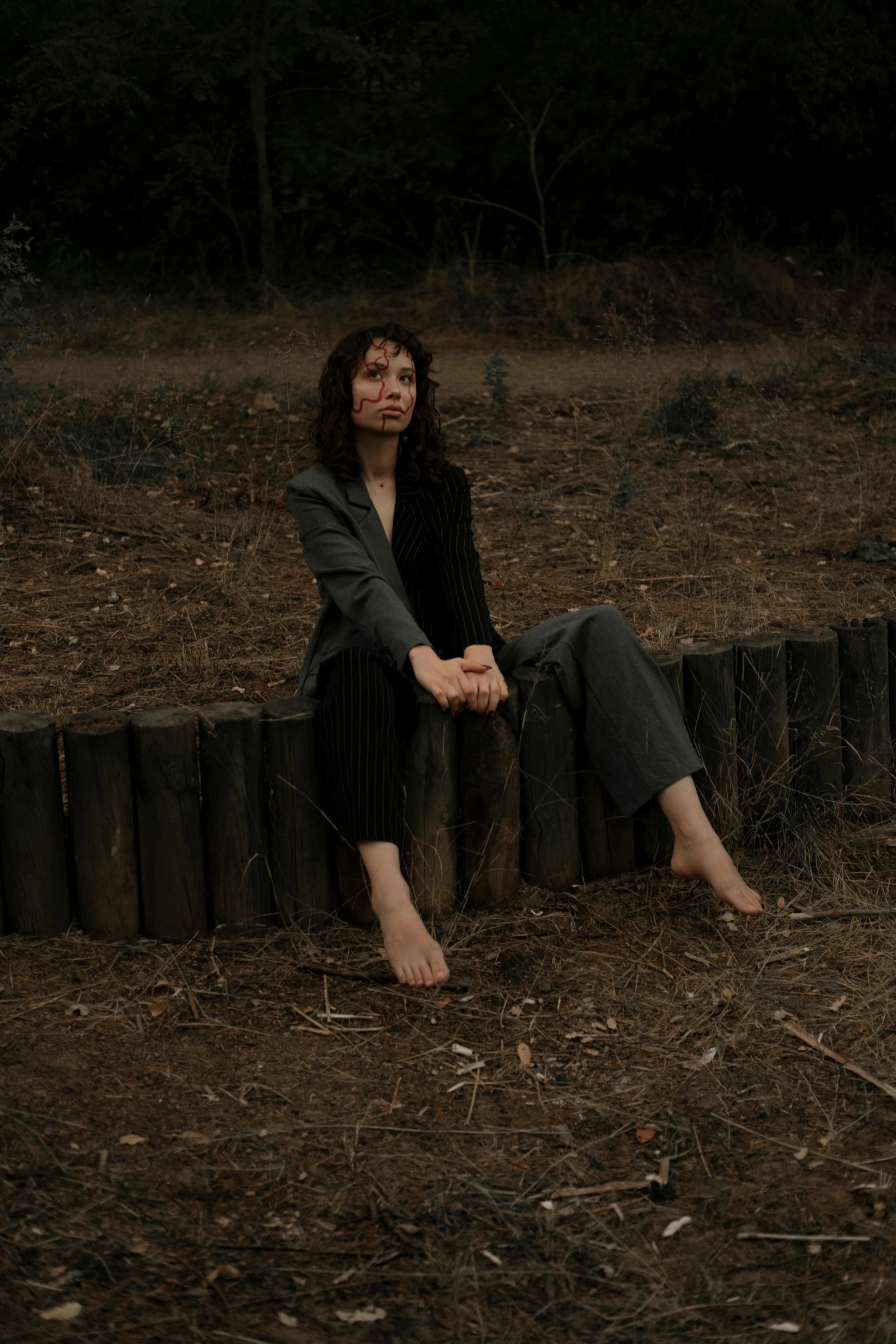 a woman sits on a fence looking up at the sky