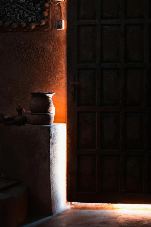 the interior of an adobe home with a dark door and light shining in