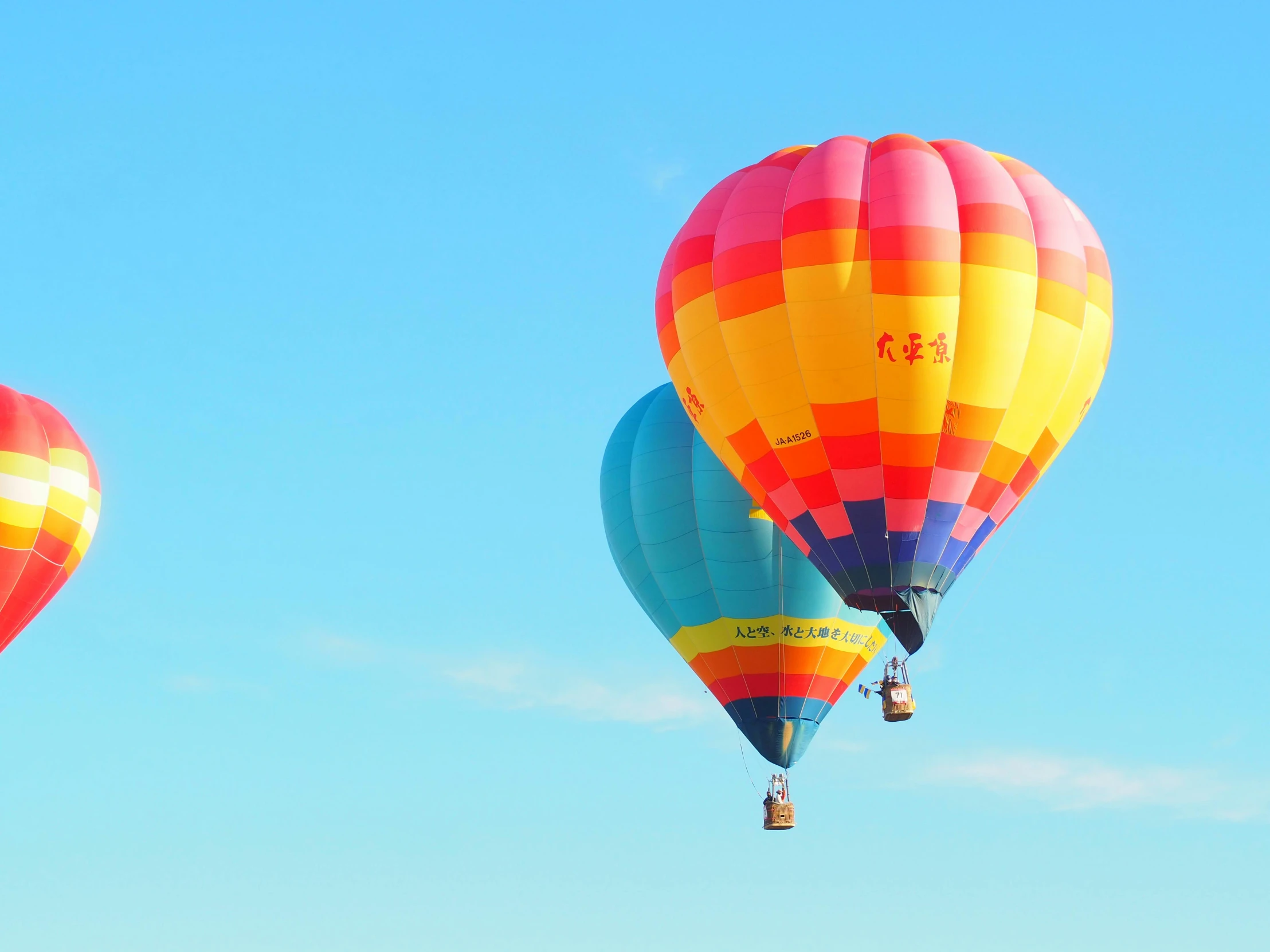 three multicolored  air balloons are flying in the sky