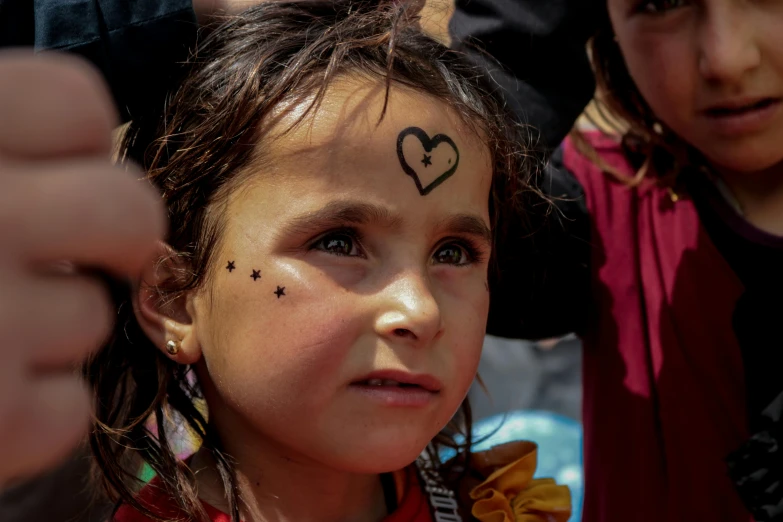 a small girl with some little cross marks on her forehead