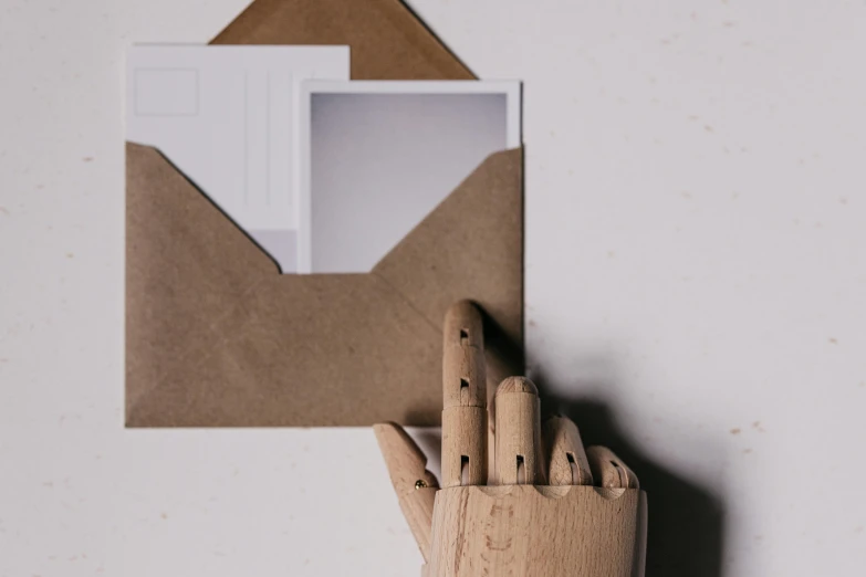 wooden block in the shape of an envelope with a pen stuck into it