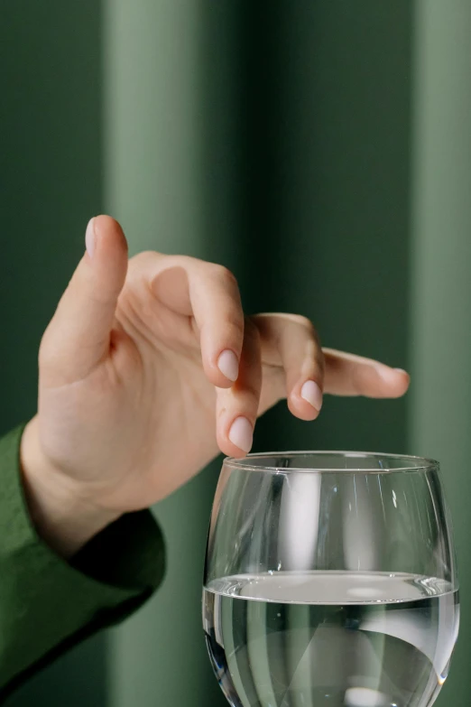 a woman points at a glass with water in it