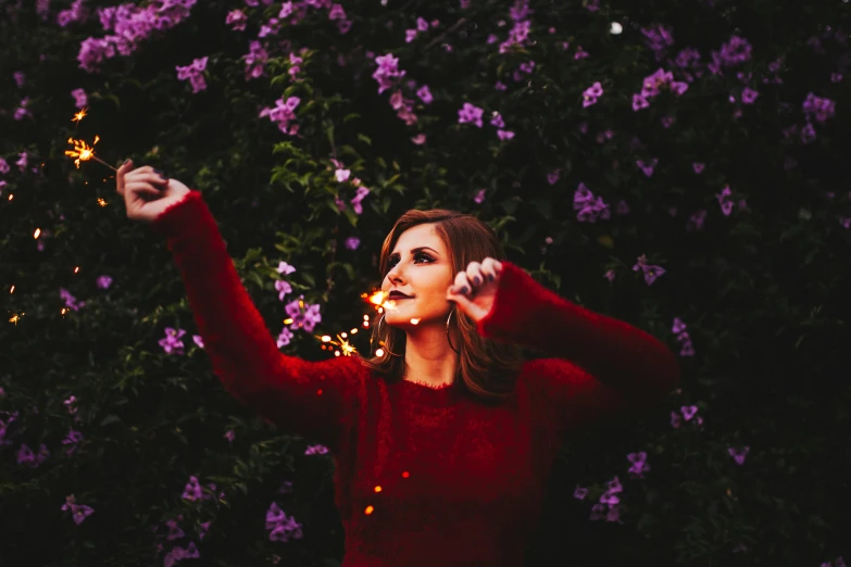 a young woman is holding a lit sparkler in her hands