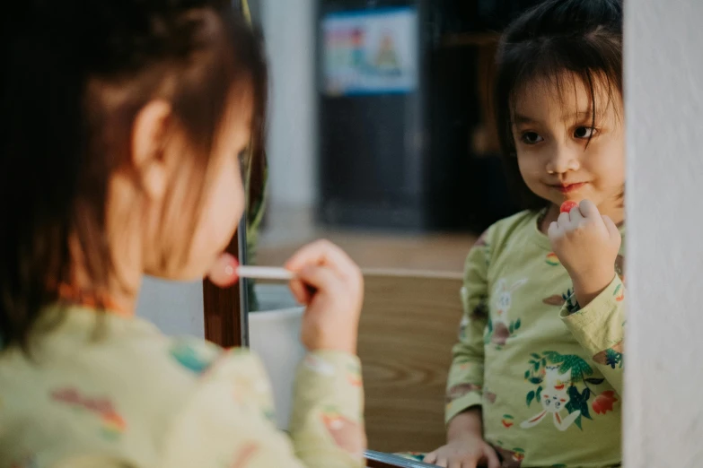 a girl brushing her teeth in front of a mirror