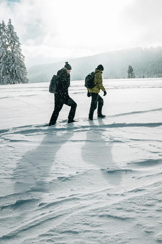 two snowboarders make their way across the snowy surface