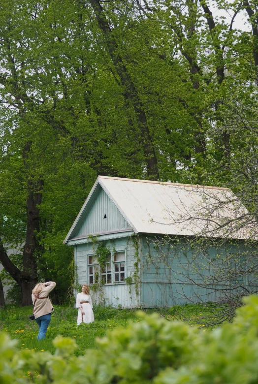 the woman and girl are standing outside a cottage