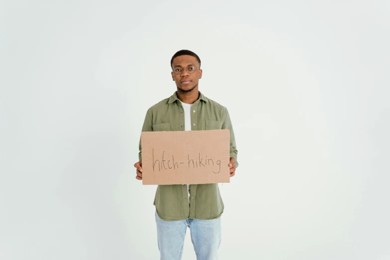man holding up a cardboard sign with a message written in it