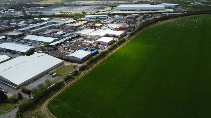 an aerial view of an industrial estate area with a huge green field in the foreground