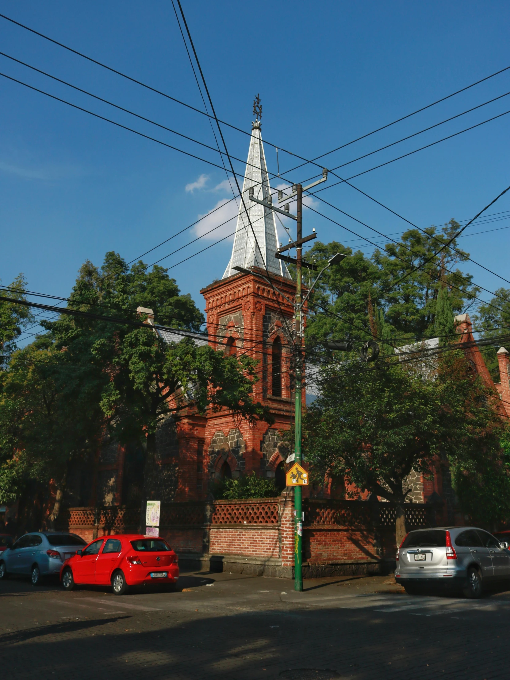 a church sits in the middle of an intersection with parked cars