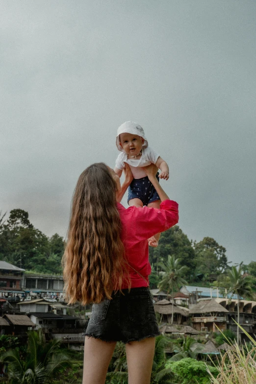 the woman holds the child while he looks at the trees