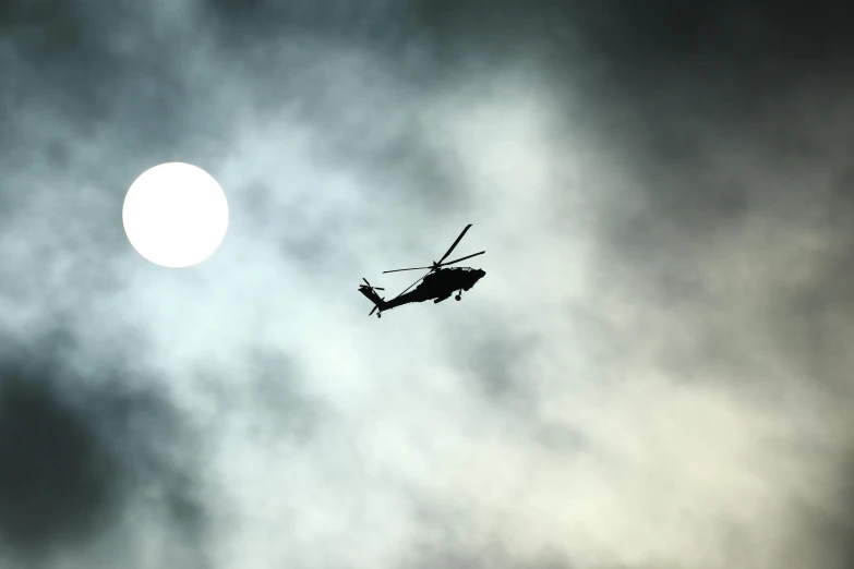 the helicopter flies through the sky with a sun in the background