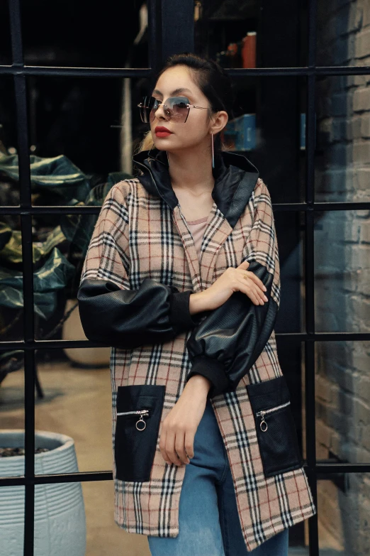 a woman wearing sunglasses and a coat standing outside