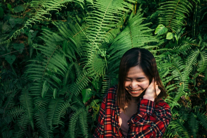 a woman smiles while standing amongst the ferns