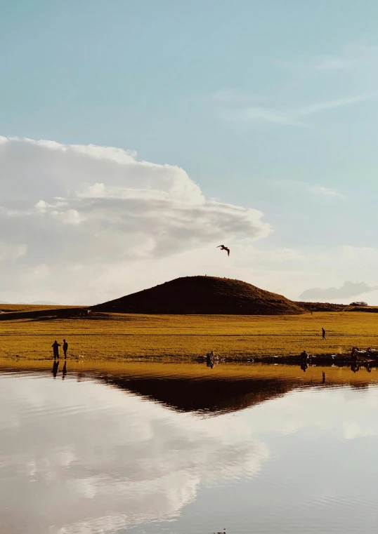 two people on an empty open field by some water